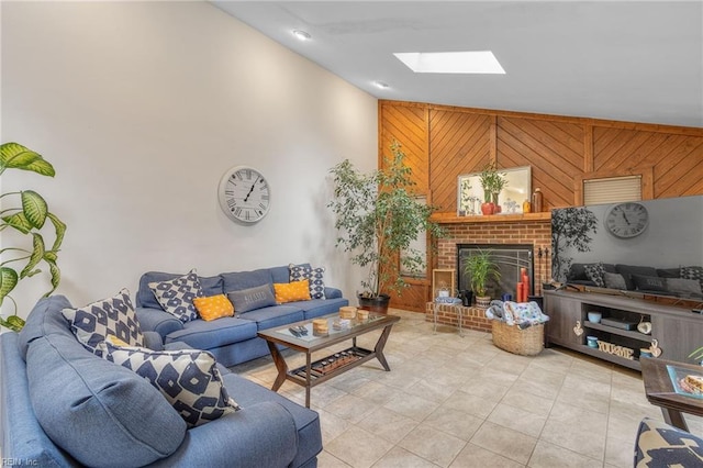 living room with wood walls, light tile patterned floors, a skylight, and a brick fireplace