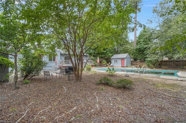 view of yard featuring a fenced in pool and a storage shed