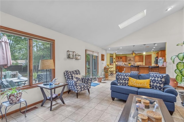 living room featuring high vaulted ceiling, a skylight, and light tile patterned floors