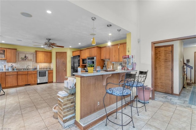 kitchen featuring hanging light fixtures, a kitchen breakfast bar, kitchen peninsula, black refrigerator with ice dispenser, and ceiling fan