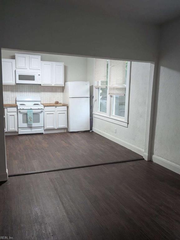 kitchen featuring backsplash, white appliances, white cabinetry, and dark hardwood / wood-style floors