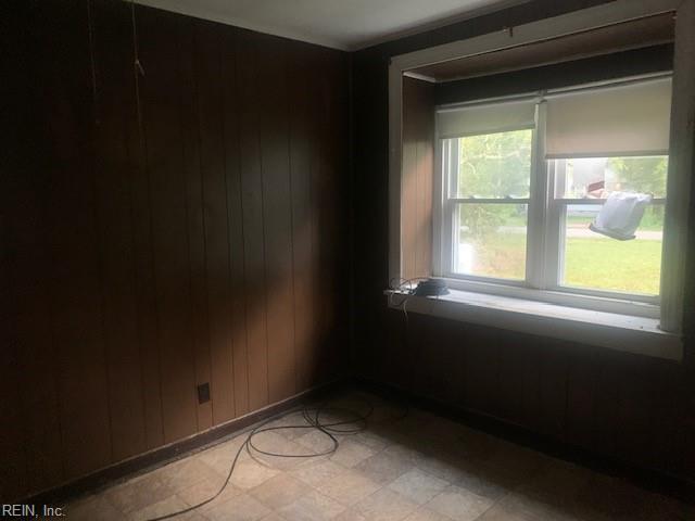 empty room featuring a wealth of natural light and wood walls