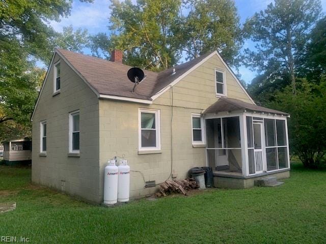 back of property with a yard and a sunroom