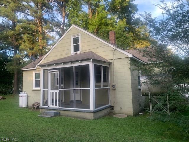 rear view of property featuring a lawn and a sunroom