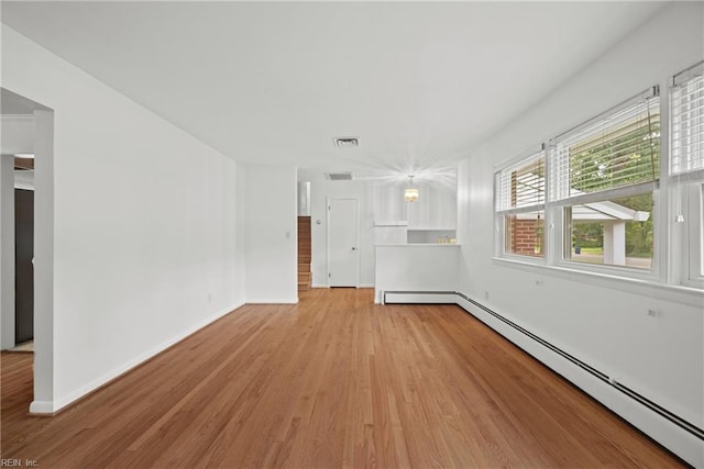 unfurnished room featuring baseboard heating and light hardwood / wood-style floors