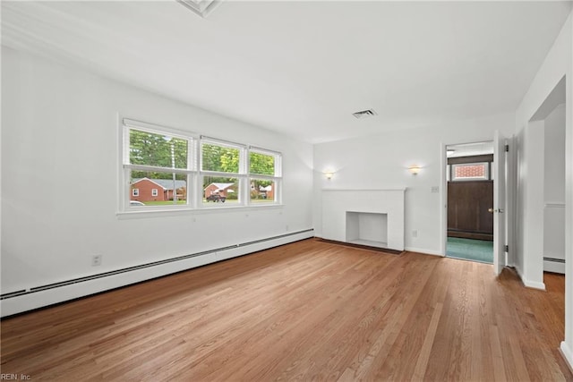 unfurnished living room with baseboard heating, hardwood / wood-style flooring, and a fireplace