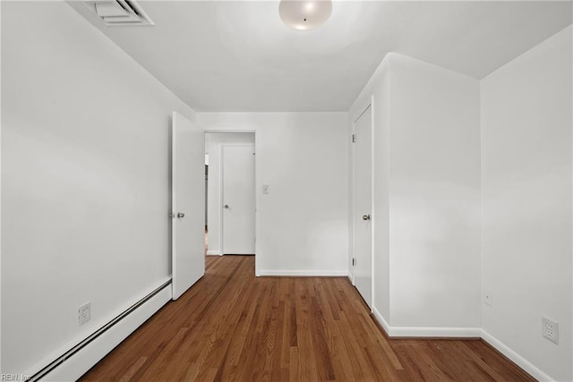 unfurnished bedroom with wood-type flooring and a baseboard radiator