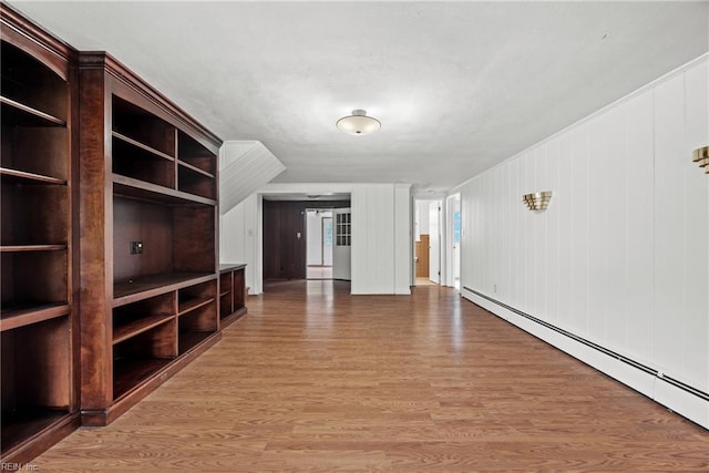 unfurnished living room with baseboard heating, hardwood / wood-style floors, and wooden walls