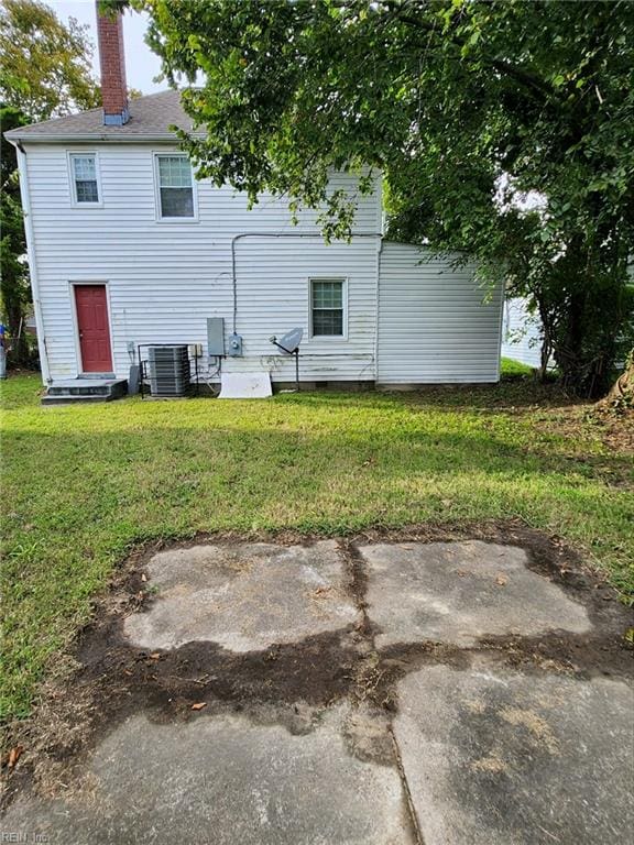 back of property featuring central air condition unit and a yard