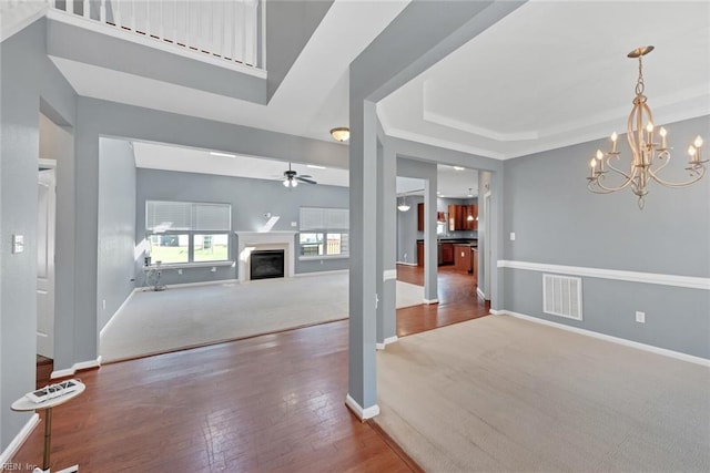 foyer featuring visible vents, a tray ceiling, hardwood / wood-style floors, a fireplace, and baseboards