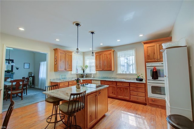 kitchen with a center island, light hardwood / wood-style flooring, hanging light fixtures, and white double oven