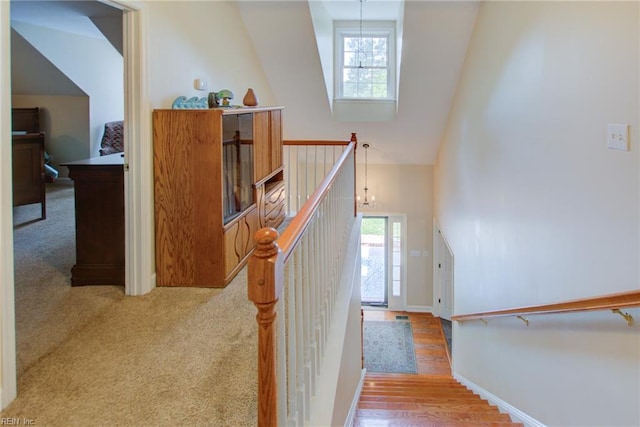 stairs with high vaulted ceiling, hardwood / wood-style flooring, and a notable chandelier