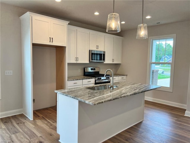 kitchen with light hardwood / wood-style flooring, appliances with stainless steel finishes, light stone countertops, sink, and a kitchen island with sink