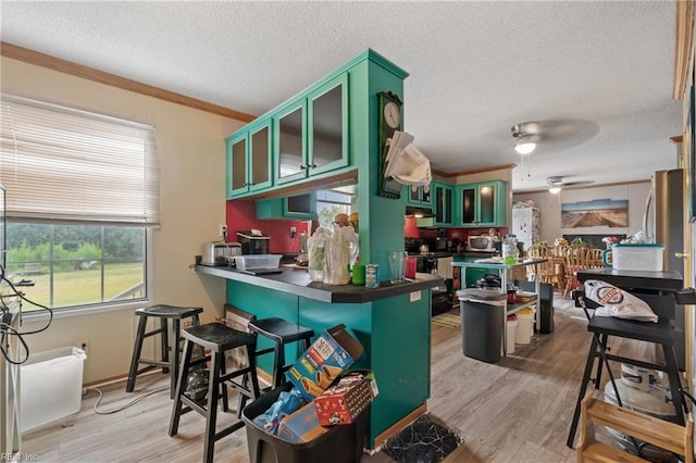 kitchen with black range with electric stovetop, light wood-type flooring, ornamental molding, a textured ceiling, and green cabinetry