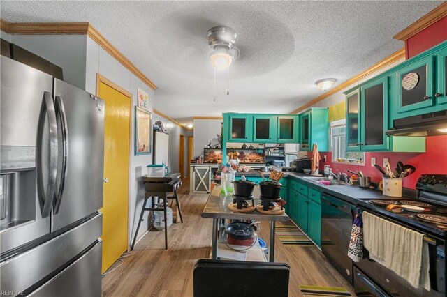 kitchen featuring light wood-type flooring, black appliances, under cabinet range hood, a sink, and green cabinets