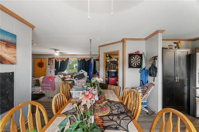 dining room featuring a ceiling fan, a textured ceiling, wood finished floors, and ornamental molding