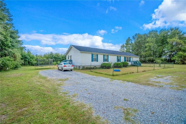 view of front of house with a front yard, driveway, a fenced front yard, crawl space, and a trampoline