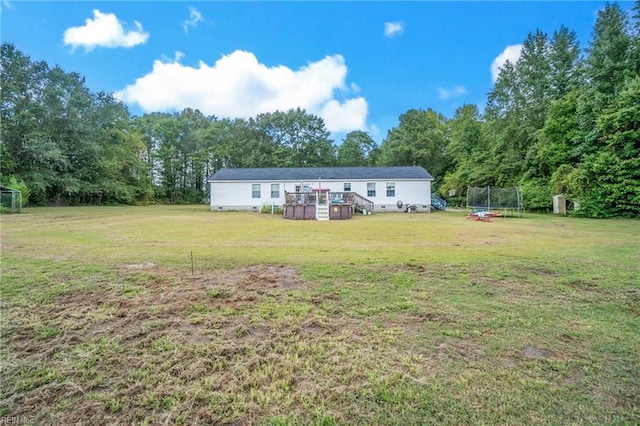 exterior space with crawl space, a trampoline, a wooden deck, and a front lawn