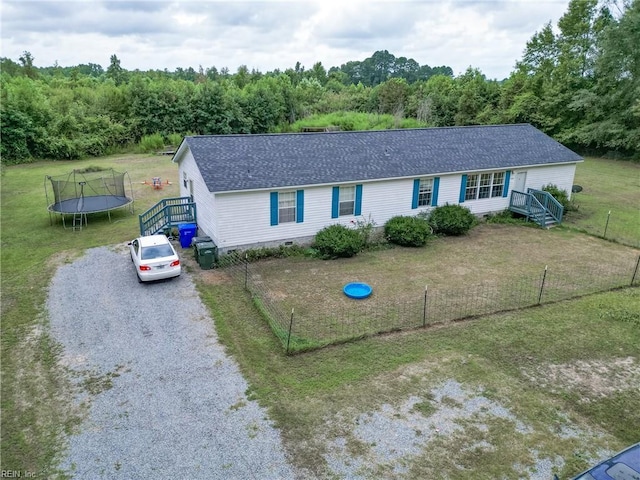 single story home featuring crawl space, a trampoline, gravel driveway, and a front lawn