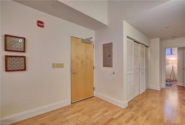 corridor with electric panel and light hardwood / wood-style flooring