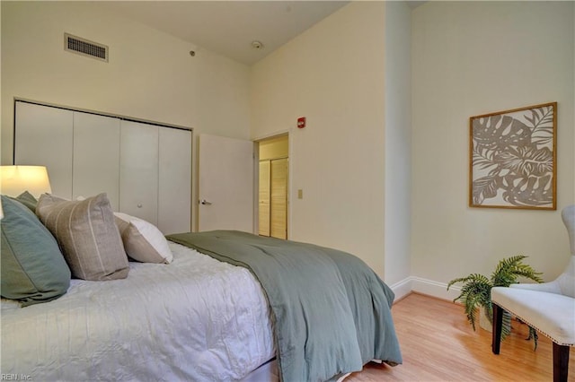 bedroom with light wood-type flooring and high vaulted ceiling