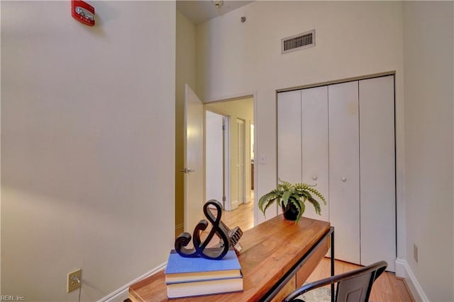 office with a towering ceiling and light hardwood / wood-style floors