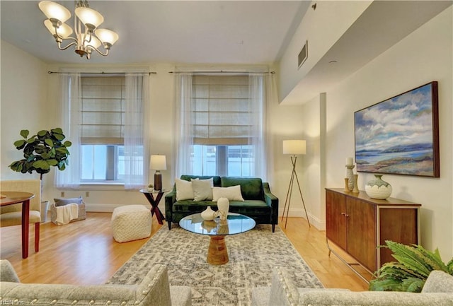 sitting room with a healthy amount of sunlight, an inviting chandelier, and wood-type flooring