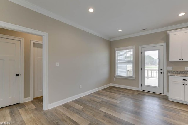 unfurnished dining area featuring light hardwood / wood-style floors and ornamental molding