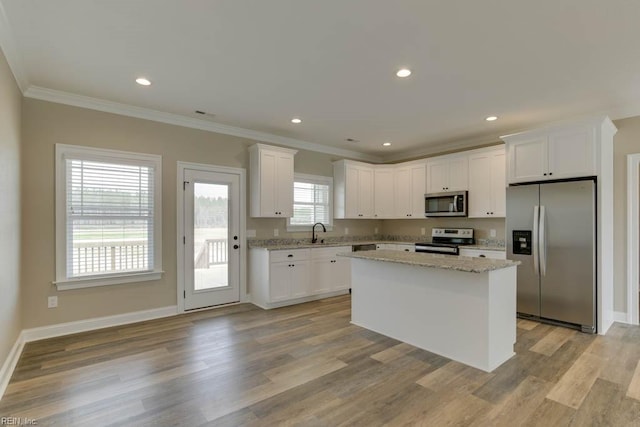 kitchen featuring appliances with stainless steel finishes, light hardwood / wood-style flooring, a kitchen island, and white cabinets