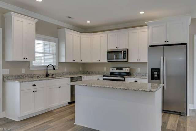 kitchen with a center island, stainless steel appliances, white cabinetry, and light hardwood / wood-style floors