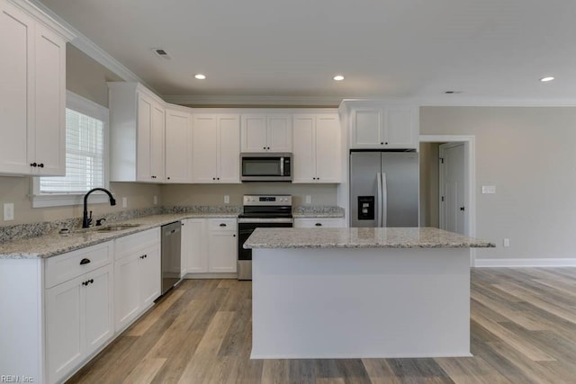 kitchen featuring a center island, light wood-type flooring, stainless steel appliances, white cabinetry, and sink