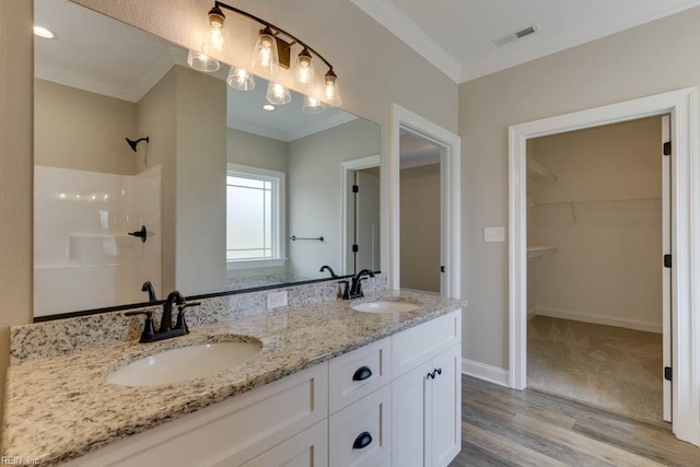 bathroom featuring hardwood / wood-style floors, walk in shower, crown molding, and vanity