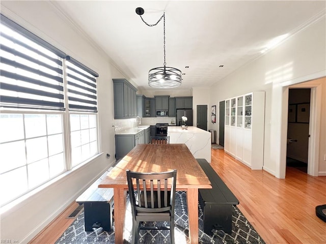 dining space with sink, crown molding, and light hardwood / wood-style flooring