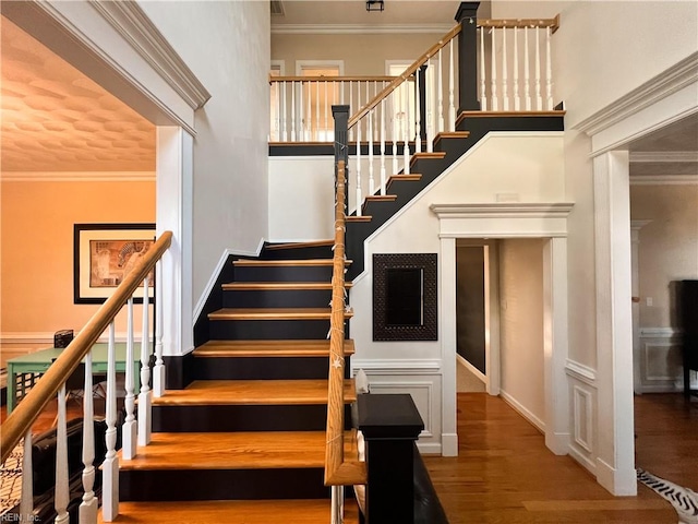 stairs with crown molding and hardwood / wood-style floors