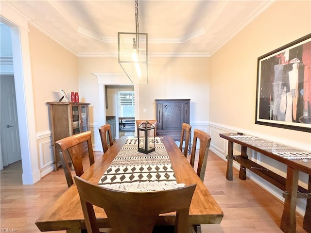 dining area featuring a raised ceiling, crown molding, and light hardwood / wood-style flooring