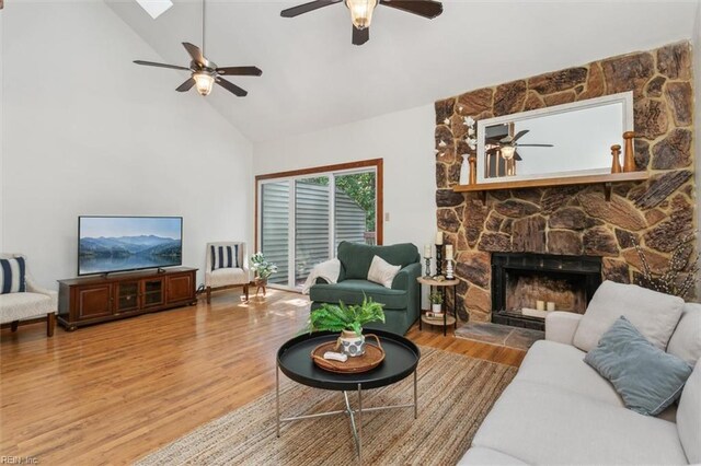 living room featuring high vaulted ceiling, ceiling fan, wood-type flooring, and a fireplace