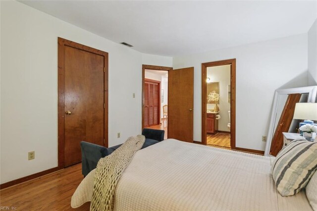 bedroom featuring light wood-type flooring, connected bathroom, and a closet