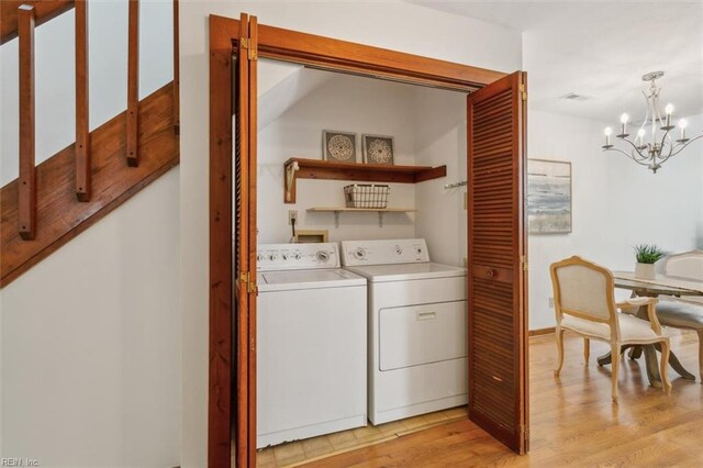 laundry room featuring washer and dryer, light hardwood / wood-style flooring, and a chandelier