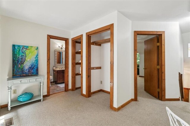 bedroom featuring ensuite bathroom and light colored carpet