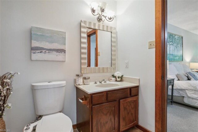 bathroom featuring vanity, toilet, and a notable chandelier