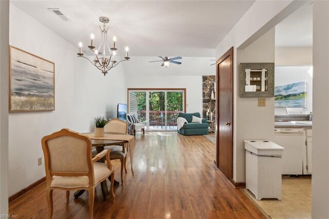 dining room with ceiling fan with notable chandelier and light hardwood / wood-style flooring