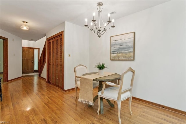 dining area with light hardwood / wood-style flooring and a notable chandelier