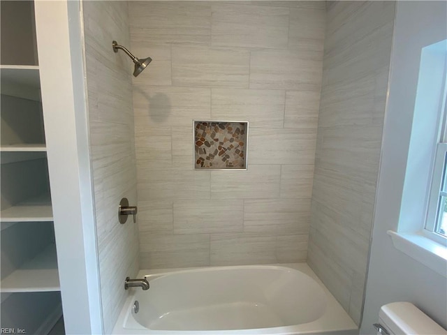 bathroom featuring toilet and tiled shower / bath