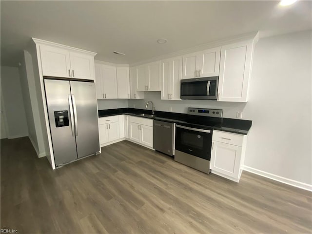 kitchen with white cabinetry, appliances with stainless steel finishes, dark hardwood / wood-style flooring, and sink