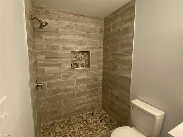 bathroom with a tile shower and toilet