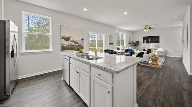 kitchen featuring a wealth of natural light, stainless steel appliances, sink, a center island with sink, and white cabinetry