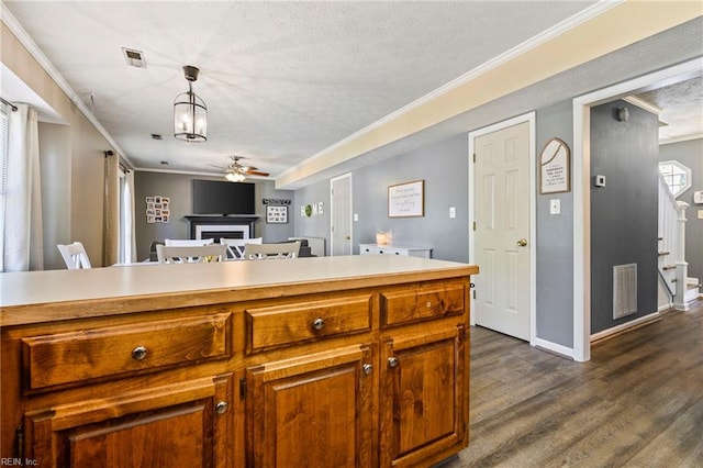 kitchen with a fireplace, visible vents, a ceiling fan, and ornamental molding
