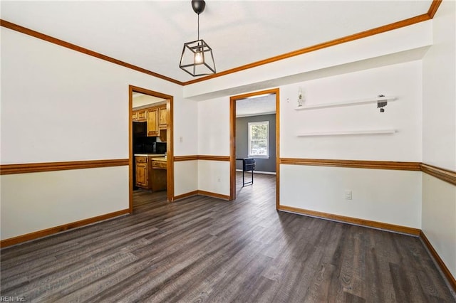 empty room featuring dark wood finished floors, baseboards, and crown molding