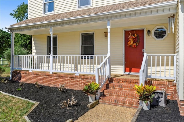 property entrance with covered porch and a shingled roof