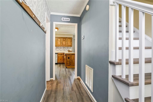 hall featuring dark wood-style flooring, a textured ceiling, visible vents, and crown molding